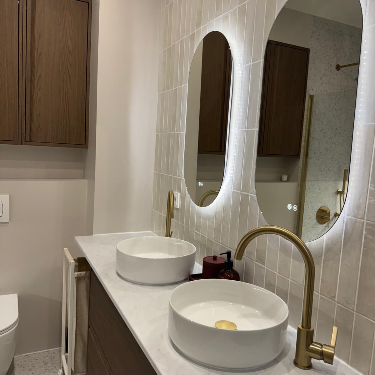 Baño con dos lavabos, dos espejos y grifos dorados