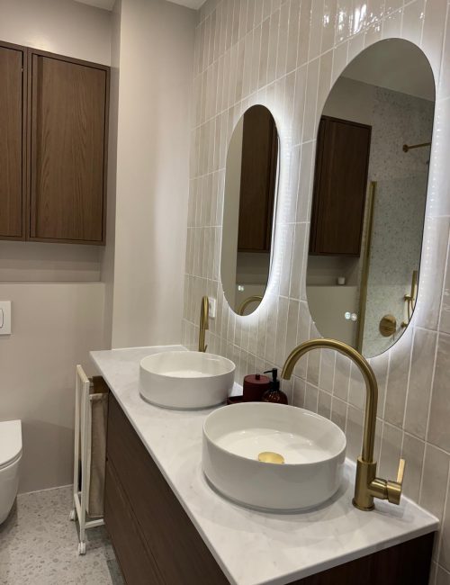 Baño con dos lavabos, dos espejos y grifos dorados