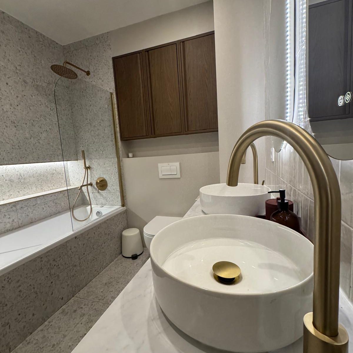 Baño con dos lavabos, dos espejos y grifos dorados