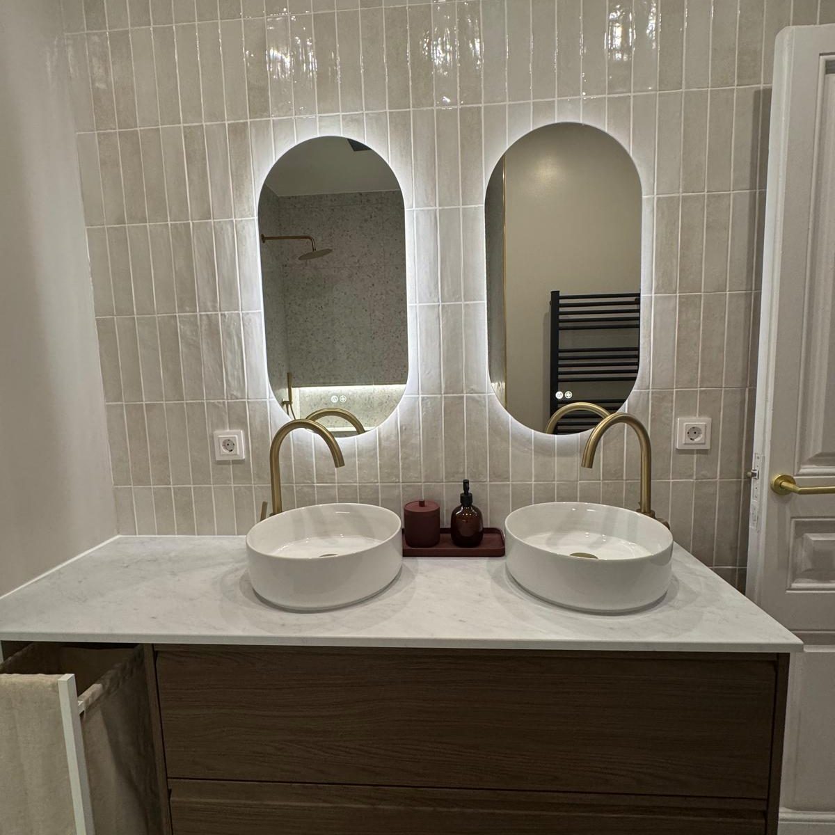 Baño con dos lavabos, dos espejos y grifos dorados