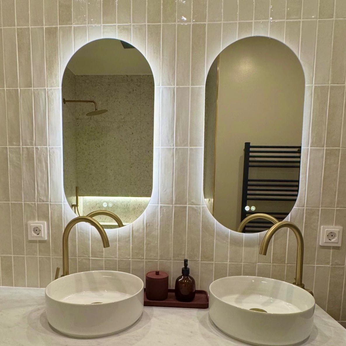 Baño con dos lavabos, dos espejos y grifos dorados