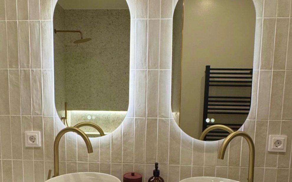 Baño con dos lavabos, dos espejos y grifos dorados